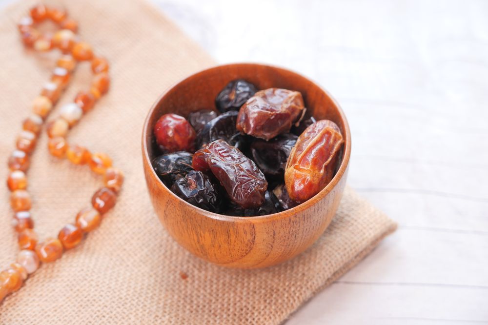 Rustic Wooden Bowl of Dates With Natural Beads on Burlap Surface