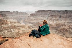 Female relaxing on cliff and admiring picturesque view