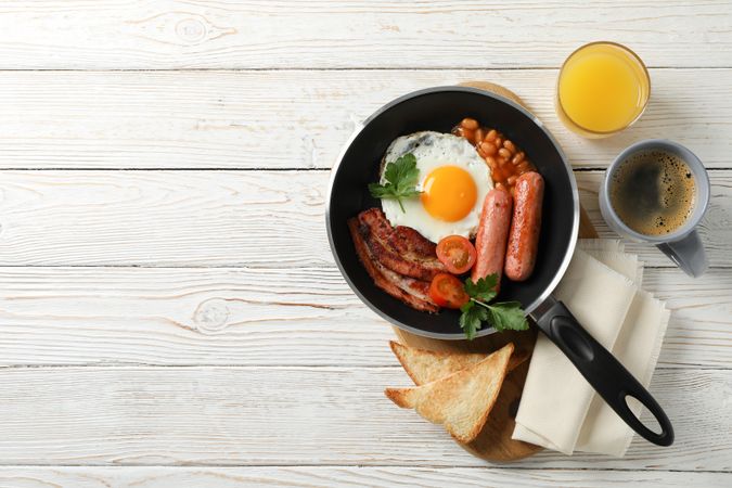 Pan of breakfast on wooden table, copy space