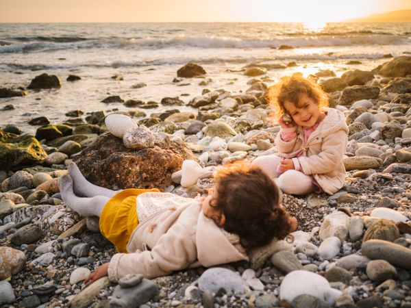 Cute girls resting on stony beach in evening