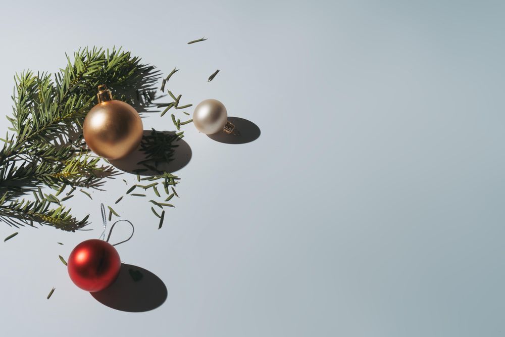 Pine branch of Christmas tree with baubles on grey background