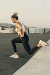 Athletic woman doing Bulgarian split squats or lunges during an outdoor workout