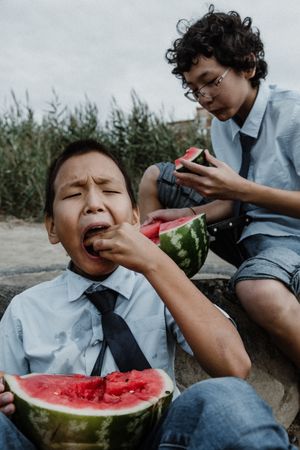 Little boys playing while eating watermelon on beach