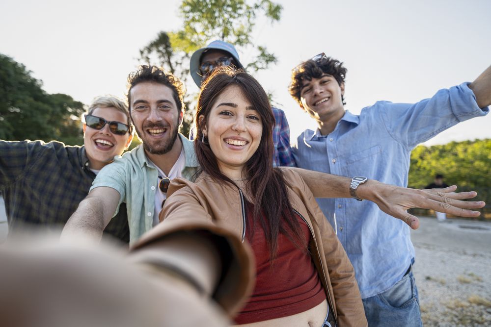 Happy diverse friends taking outdoor group selfie during summer day trip