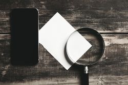 Top view of paper, cell phone magnifying glass on wooden table