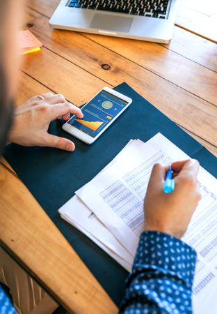 Unrecognizable businessman writing and touching mobile screen with bitcoins