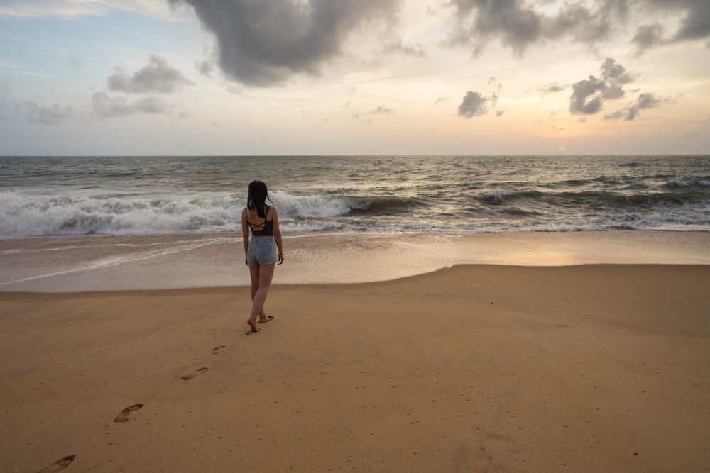 Woman in beachwear walking on sand barefoot