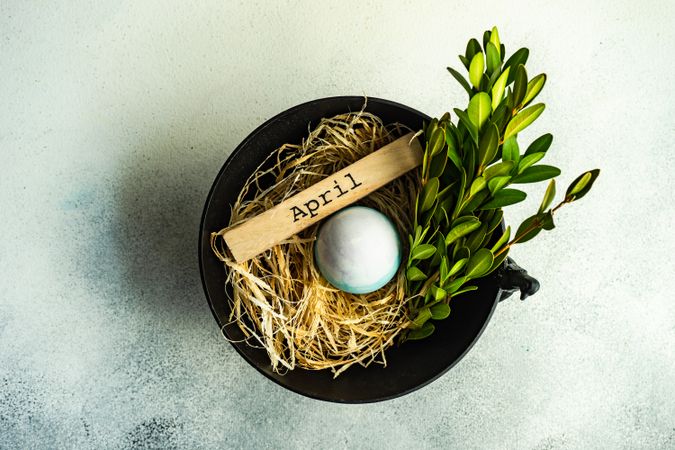 Easter card concept with top view of bowl on table with colorful egg in straw