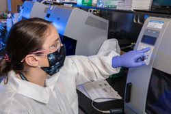 Female scientist working in a laboratory wearing a facemask and goggles 0KBD7b