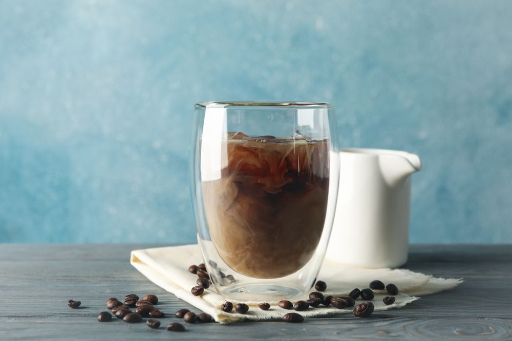 Composition with glass of ice coffee on wooden background