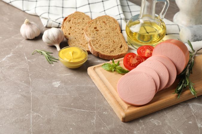 Sliced sandwich meat with bread slices, mustard and tomato, top view with copy space