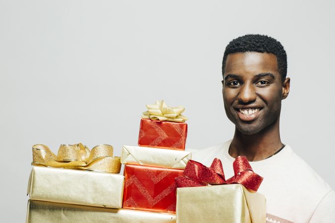 Portrait of Black man next to many wrapped presents