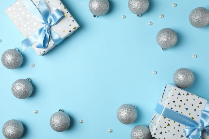 Christmas balls and presents on blue background, space for text