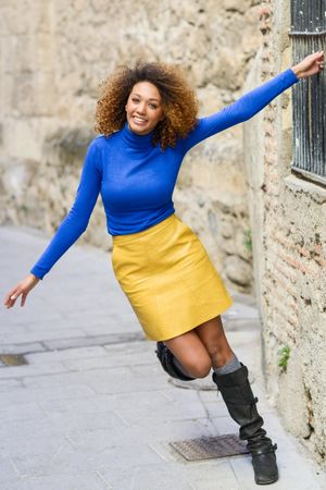 Female with curly hair wearing bright blue shirt holding bars on window on street
