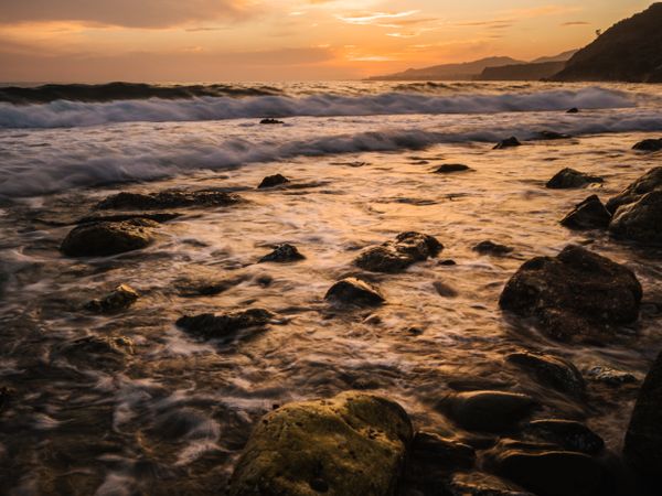 Stony seashore and waves at beautiful sunset