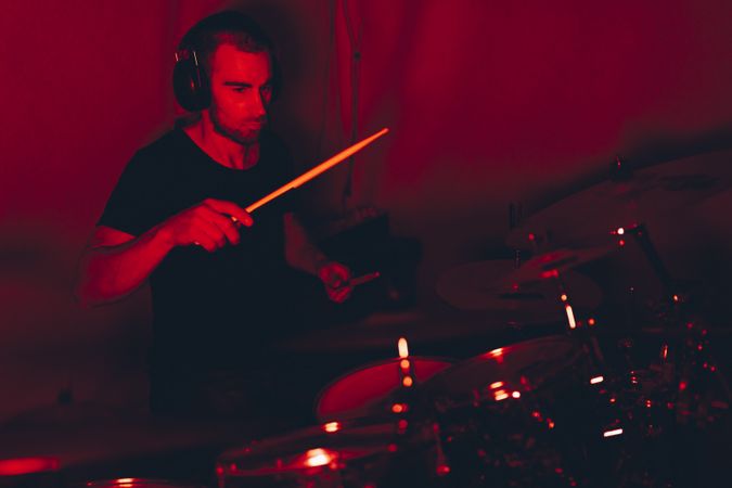 Man with drumsticks playing on drums in redness