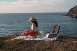 Woman reading on mat for picnic on seashore