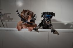 Boy in diving mask with dog in bathtub