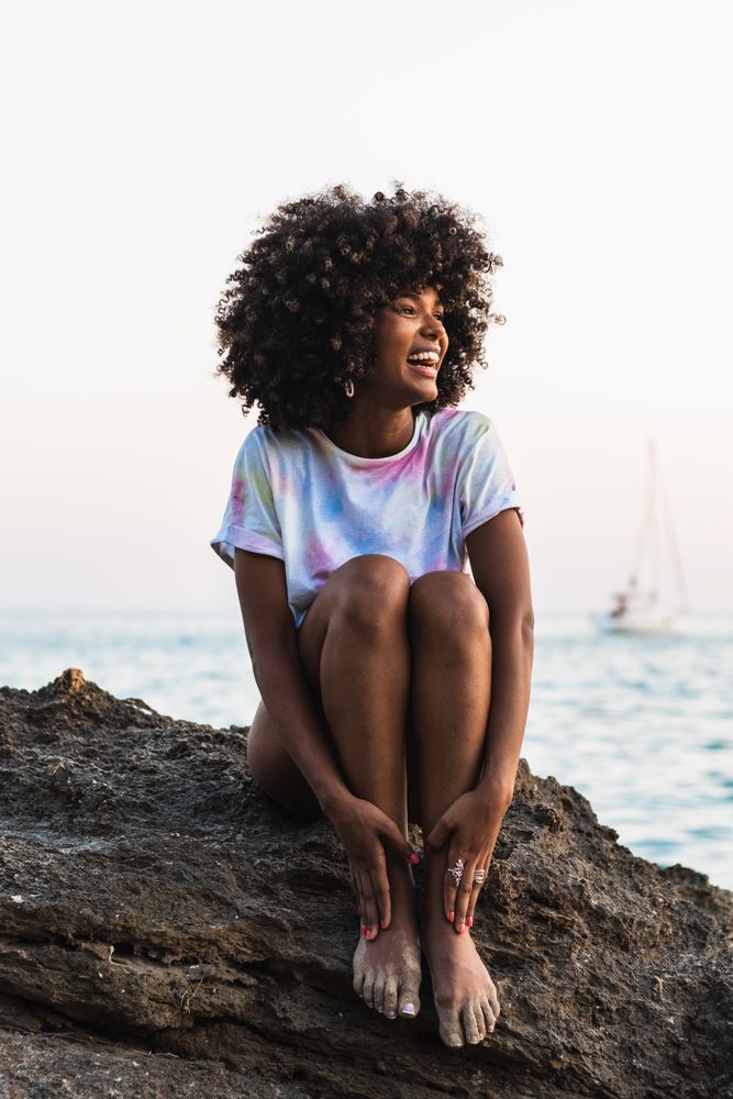 Delighted Black woman laughing at seaside