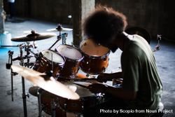 Back view of man playing drums in spacious garage bewEP5