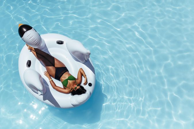 Female sunbathing on inflatable toy floating in swimming pool