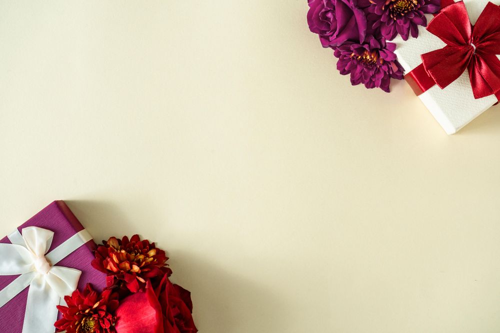 Festive presents with bows, and pink and red flowers on yellow background