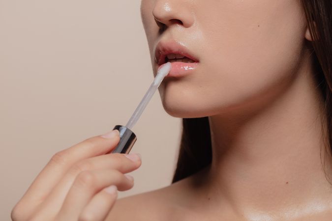 Close up of woman applying lip gloss