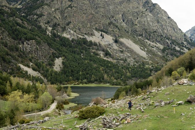 Unrecognizable traveling woman in green valley near mountains
