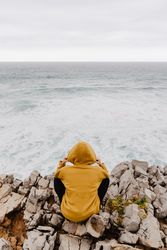 Person in yellow hoodie on stony shore