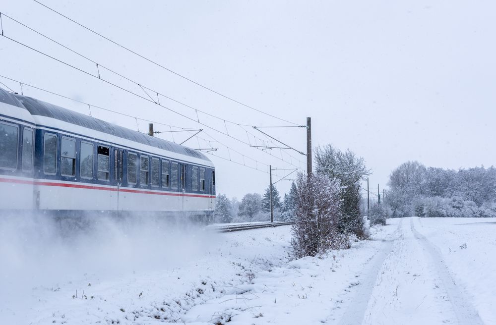 Passenger train passing through snowy fields in Germany