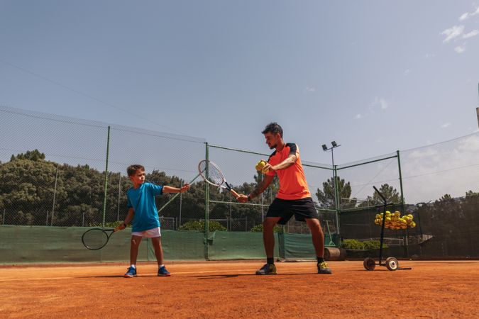 Man coaching a boy in tennis