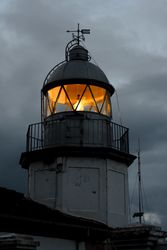 Shining lighthouse against cloudy sky