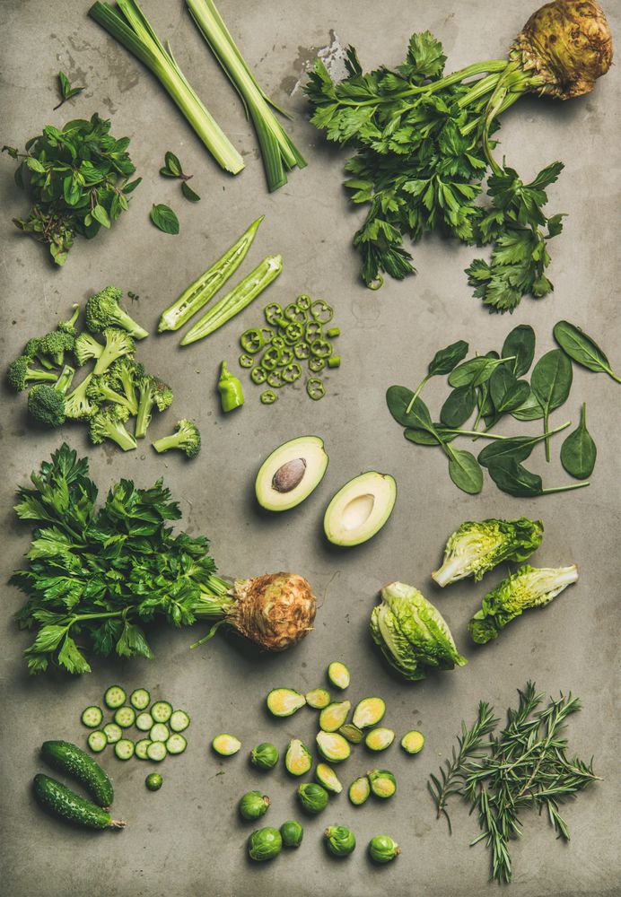 Arrangement of fresh green sliced garden vegetables on concrete surface