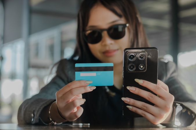 Woman Demonstrates Mobile Payments with Card and Phone, Indoors