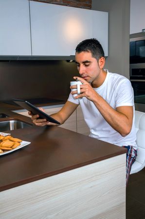 Man reading digital tablet while sipping coffee