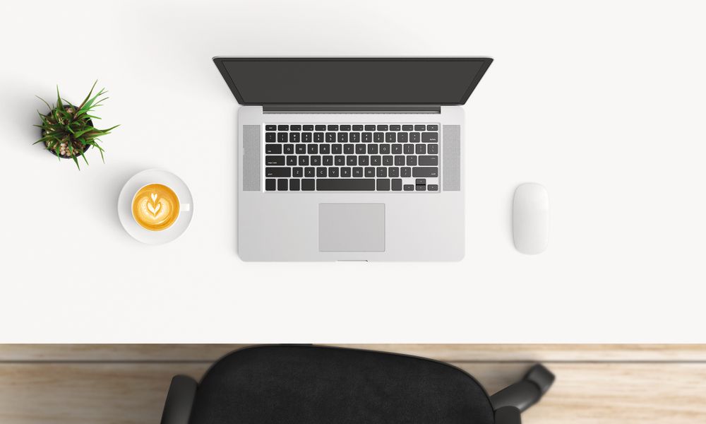 Modern workplace with laptop, coffee cup and notebook copy space on table background. Top view. Flat lay style.