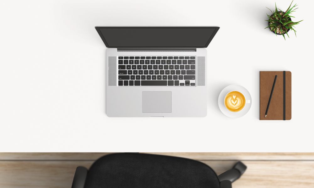 Modern workplace with laptop, coffee cup and notebook copy space on table background. Top view. Flat lay style.
