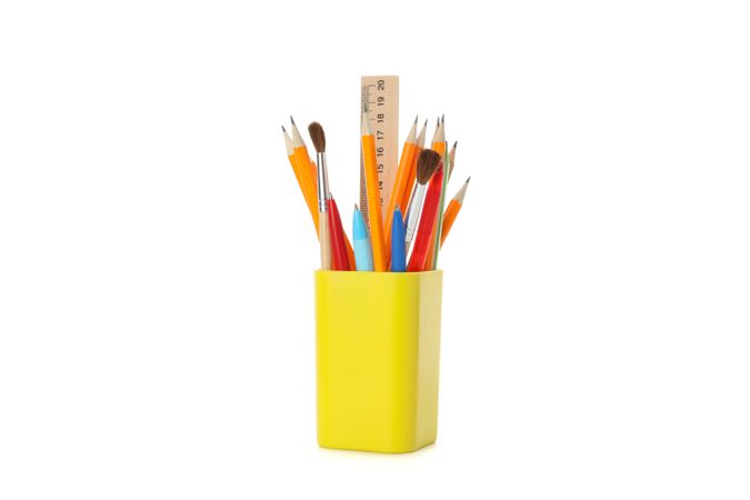 Yellow pencil holder filled with pencils, pens and ruler