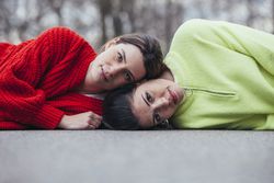 Women in sweaters lying on asphalt