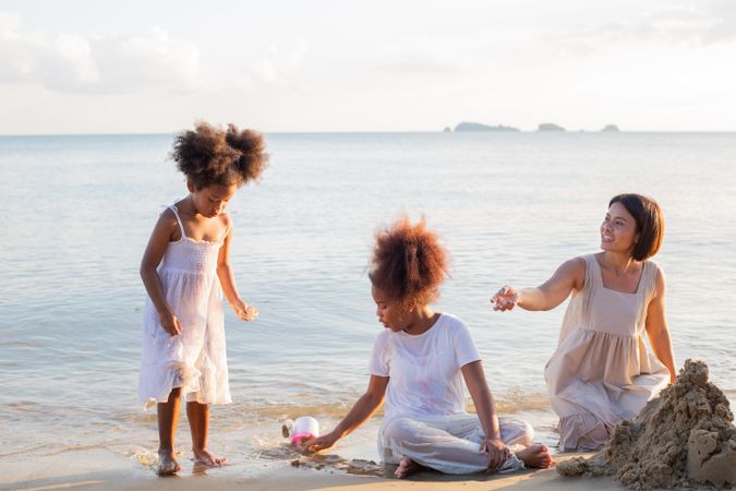 Family playing and building sand castle at tropical beach in summer