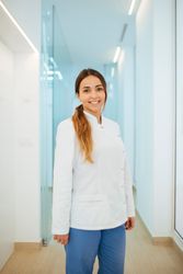 Confident dentist in uniform with crossed arms looking at camera