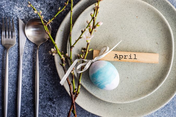Pastel Easter eggs & branch on ceramic grey plate with silverware