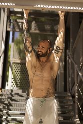 Muscular guy performing pull ups on street