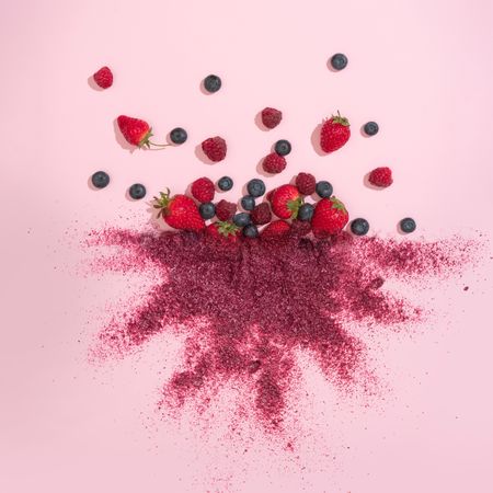 Mixed berries with red dust on pink background