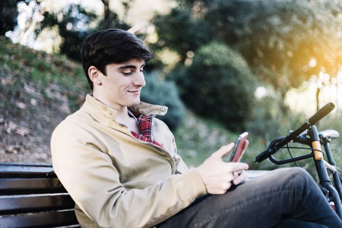 Content man texting on mobile phone while sitting outdoors