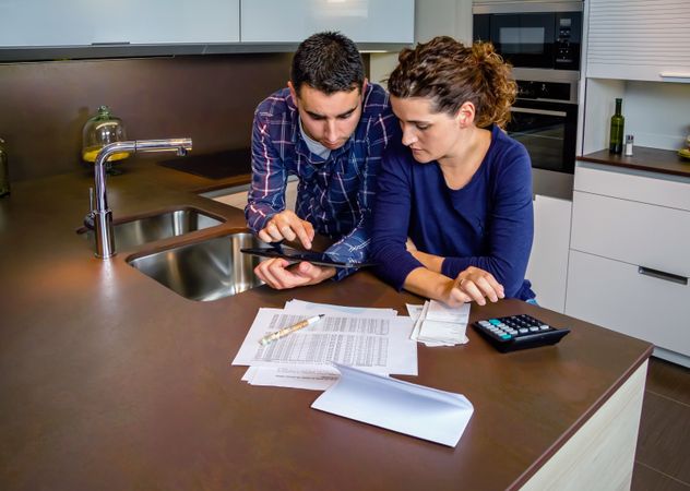 Couple reviewing their monthly bills on kitchen counter
