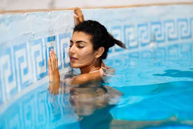 Beautiful Arab woman relaxing in swimming pool with eyes close
