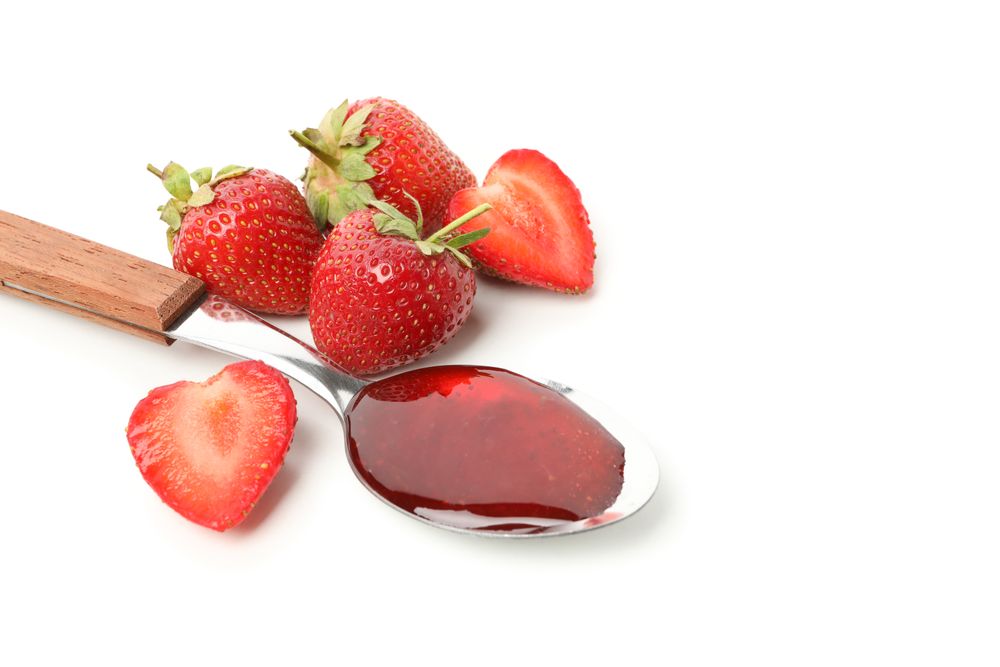 Strawberry and spoon with strawberry jam isolated on plain background