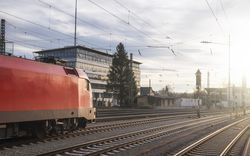 Red locomotive on railroad tracks at sunset
