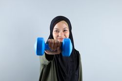 Sporty Muslim Indonesian Woman training with Blue Dumbbells